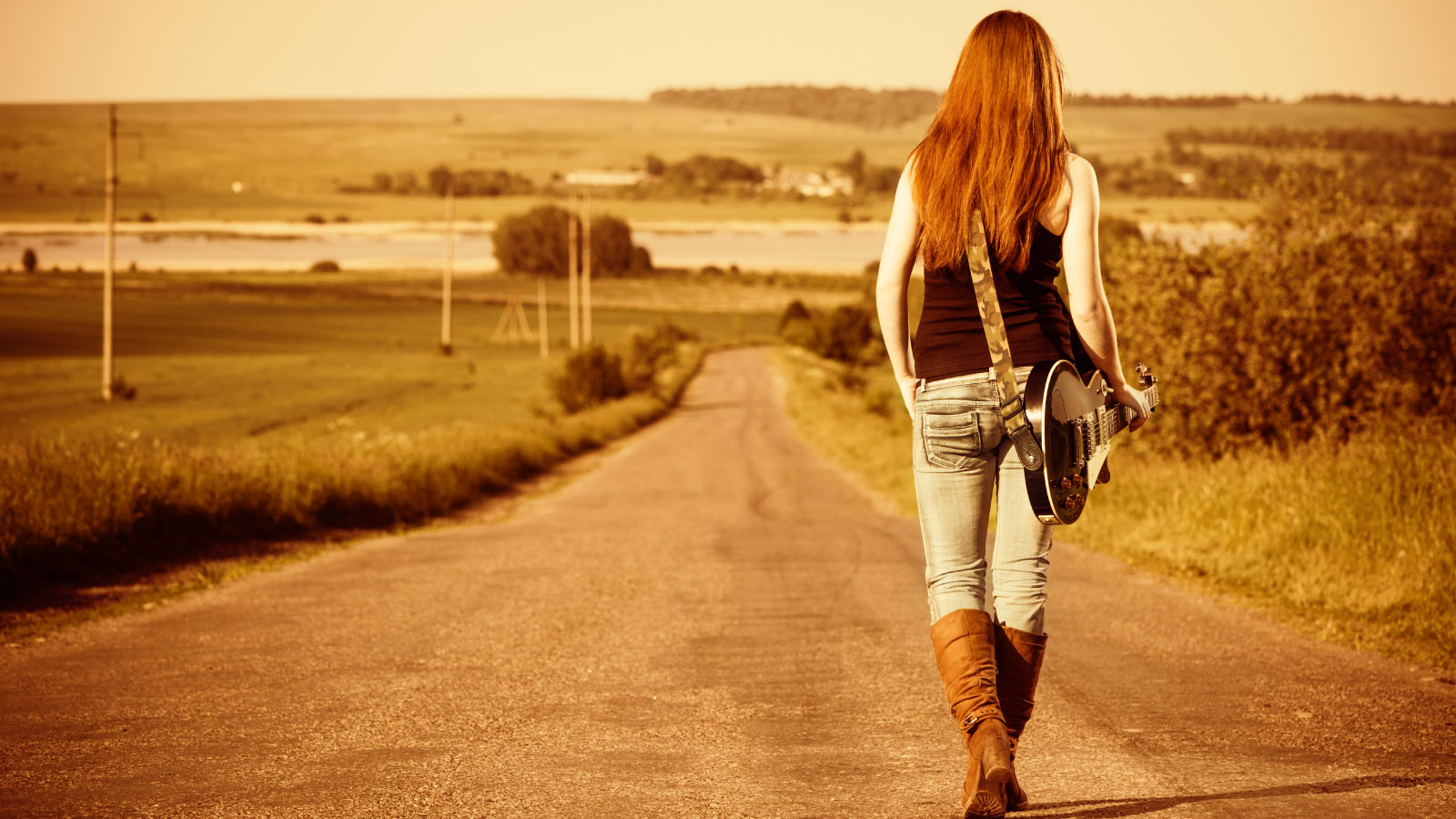 Woman with guitar on the country road